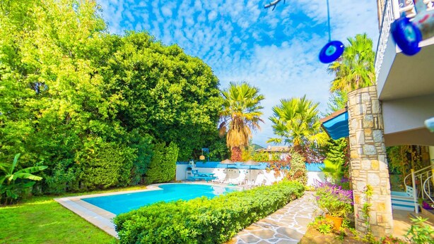 A swimming pool surrounded by lush greenery and stone pathways. - Villa Garden Island in Dalyan (Ortaca)
