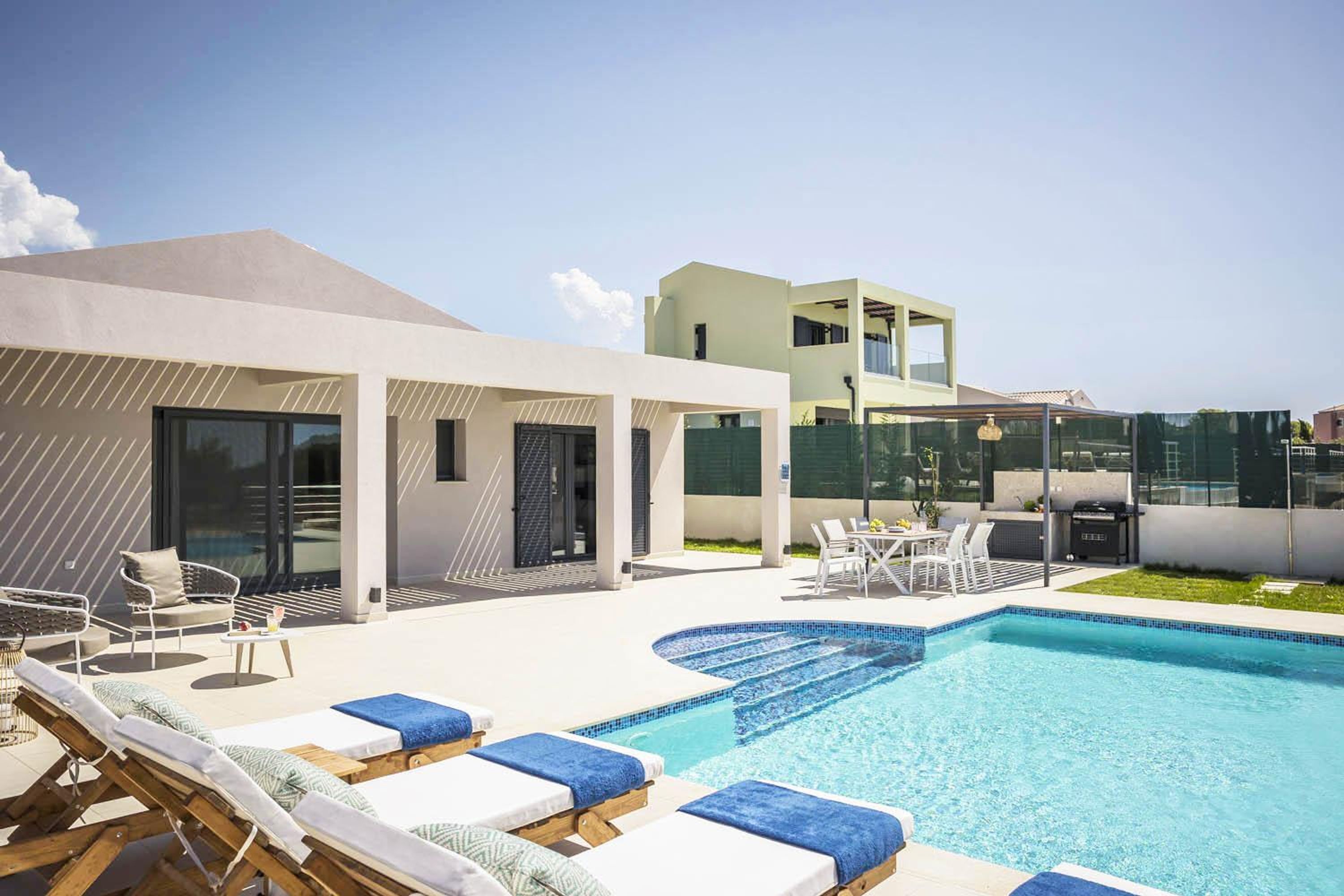 A modern outdoor pool area with lounge chairs and a dining table.