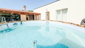 A clear swimming pool with a ladder, a covered area, and a white building with a tiled roof. - Villa Lara in Sveti Filip i Jakov (Sveti Filip i Jakov)