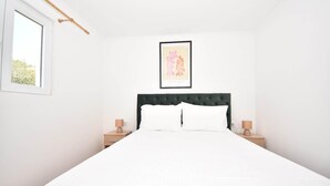 A neatly made bed with white bedding, a dark headboard, and two bedside tables with lamps. - Villa Lara in Sveti Filip i Jakov (Sveti Filip i Jakov)