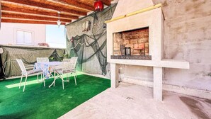 An outdoor patio with a table and chairs, a stone wall, and a fireplace. - Villa Lara in Sveti Filip i Jakov (Sveti Filip i Jakov)