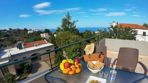 A balcony with a table set with fruits, a bowl of bread, and olives, overlooking a coastal view. - Villa Phedra in Kefalas (Apokoronas)