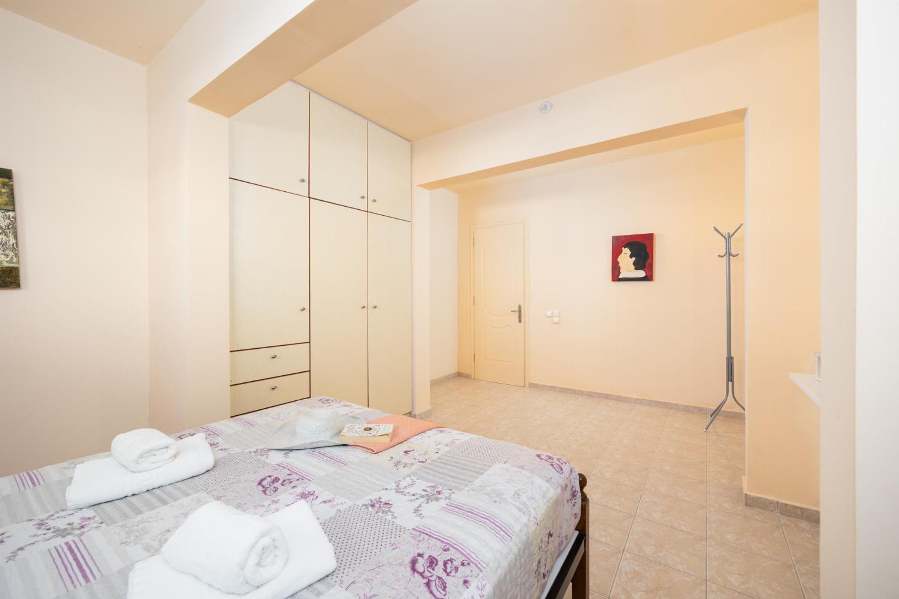 A bedroom with a bed, a wardrobe, a door, and a coat rack.