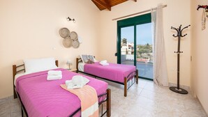 A bedroom with two beds, a balcony with a view, and a coat rack. - Villa Phedra in Kefalas (Apokoronas)