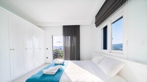 Een moderne hotelkamer met een groot bed, uitzicht op de omgeving en een balkon.