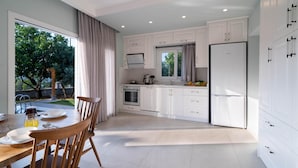 Een moderne keuken met witte kasten, een eettafel met stoelen en een groot raam.
