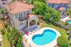 A two-story house with a swimming pool, a slide, and a patio with lounge chairs. - Villa Rosetta in Oludeniz (Fethiye)