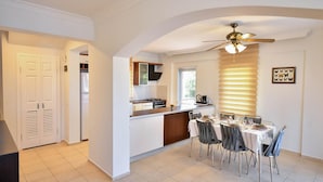 A modern kitchen with a dining area, white walls, and a ceiling fan. - Villa Rosetta in Oludeniz (Fethiye)