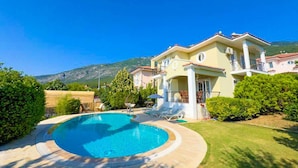 A two-story house with a swimming pool, surrounded by greenery and a mountain in the background. - Villa Rosetta in Oludeniz (Fethiye)