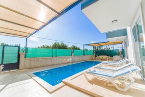 A swimming pool with lounge chairs, a covered area, and a fenced garden. - Villa Horizon in Ortaca (Ortaca)