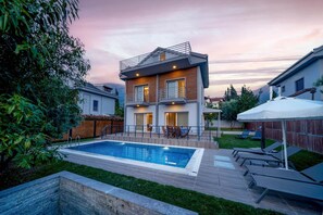 A modern two-story house with a swimming pool, a covered patio, and a fenced backyard. - Villa Riva in Oludeniz (Fethiye)
