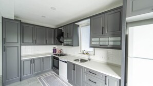 A modern kitchen with grey cabinets, white countertops, and a stainless steel sink. - Villa Maya in Ortaca (Ortaca)