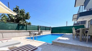 A swimming pool with a tiled deck, lounge chairs, and a covered seating area. - Villa Maya in Ortaca (Ortaca)