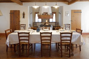 Comedor con una mesa larga dispuesta para seis personas, rodeada de sillas de madera con asientos acolchados.