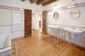 Un baño con suelo de madera, un lavabo blanco, un espejo y un perchero para toallas.