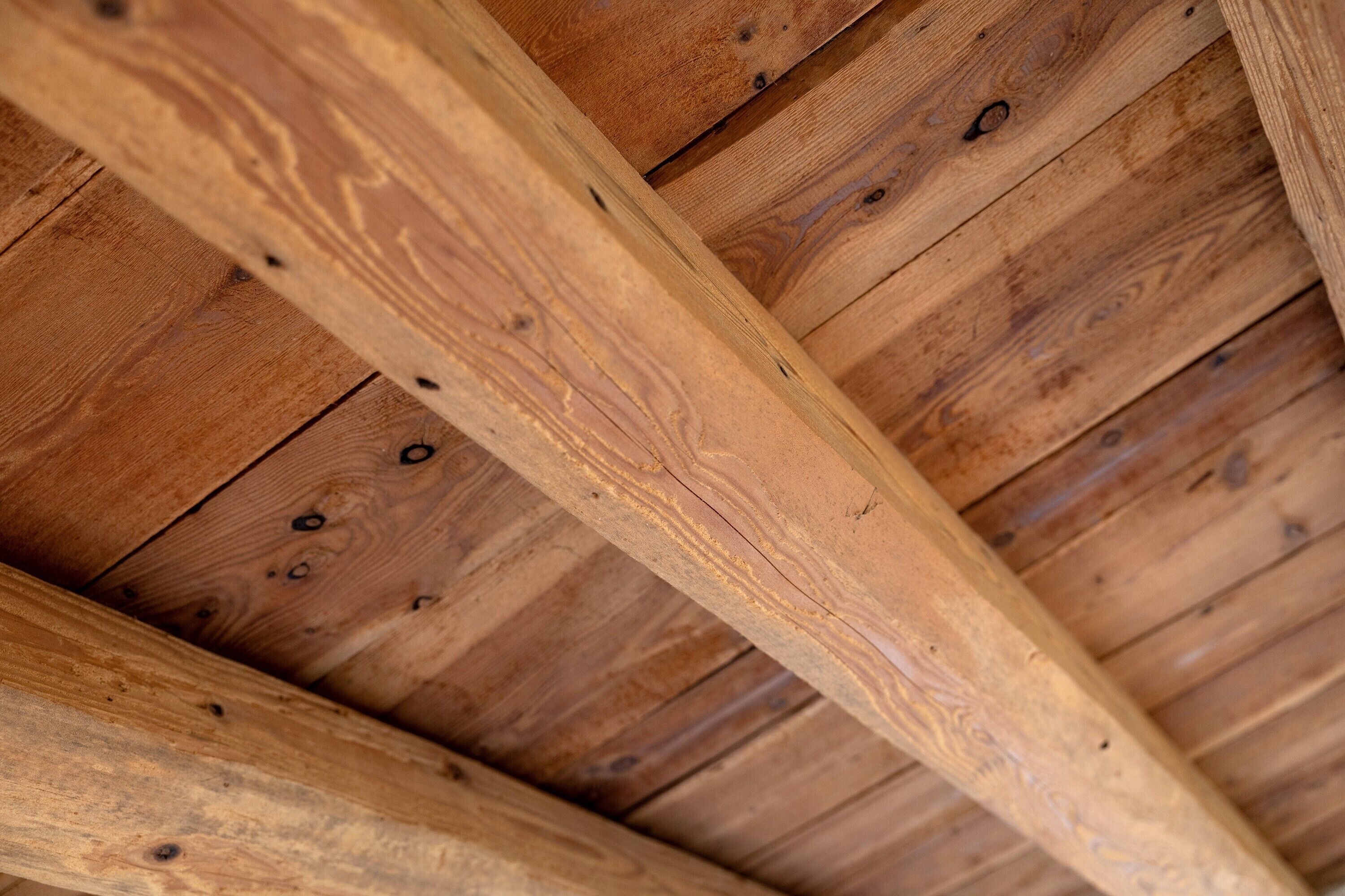 A wooden ceiling with exposed beams and a central beam structure.