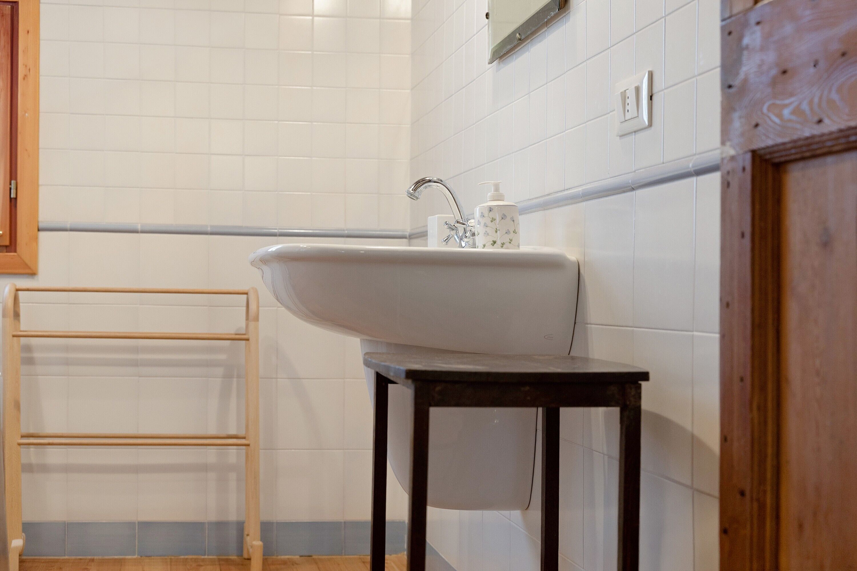 Ein Badezimmer mit Waschbecken, Handtuchhalter aus Holz und einem Holzschrank.