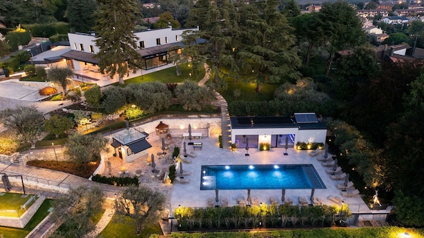 Una propiedad lujosa con una piscina grande, zona de estar al aire libre y un jardín cuidado.