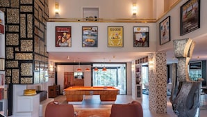 Una sala moderna con mesa de billar, puffs rojos y equipo de juego.