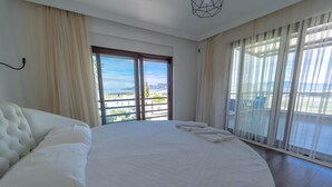 A spacious bedroom with a large bed, a view of the outdoors through a sliding glass door, and a balcony with a view. - Villa Everest in Oludeniz (Dalaman)