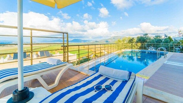 A poolside area with a view of the countryside, a pool, and lounge chairs. - Villa Everest in Oludeniz (Dalaman)