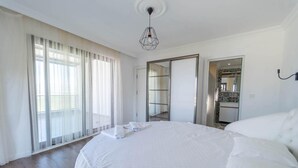 A spacious bedroom with a large bed, a walk-in closet, and a bathroom visible through an open door. - Villa Everest in Oludeniz (Dalaman)