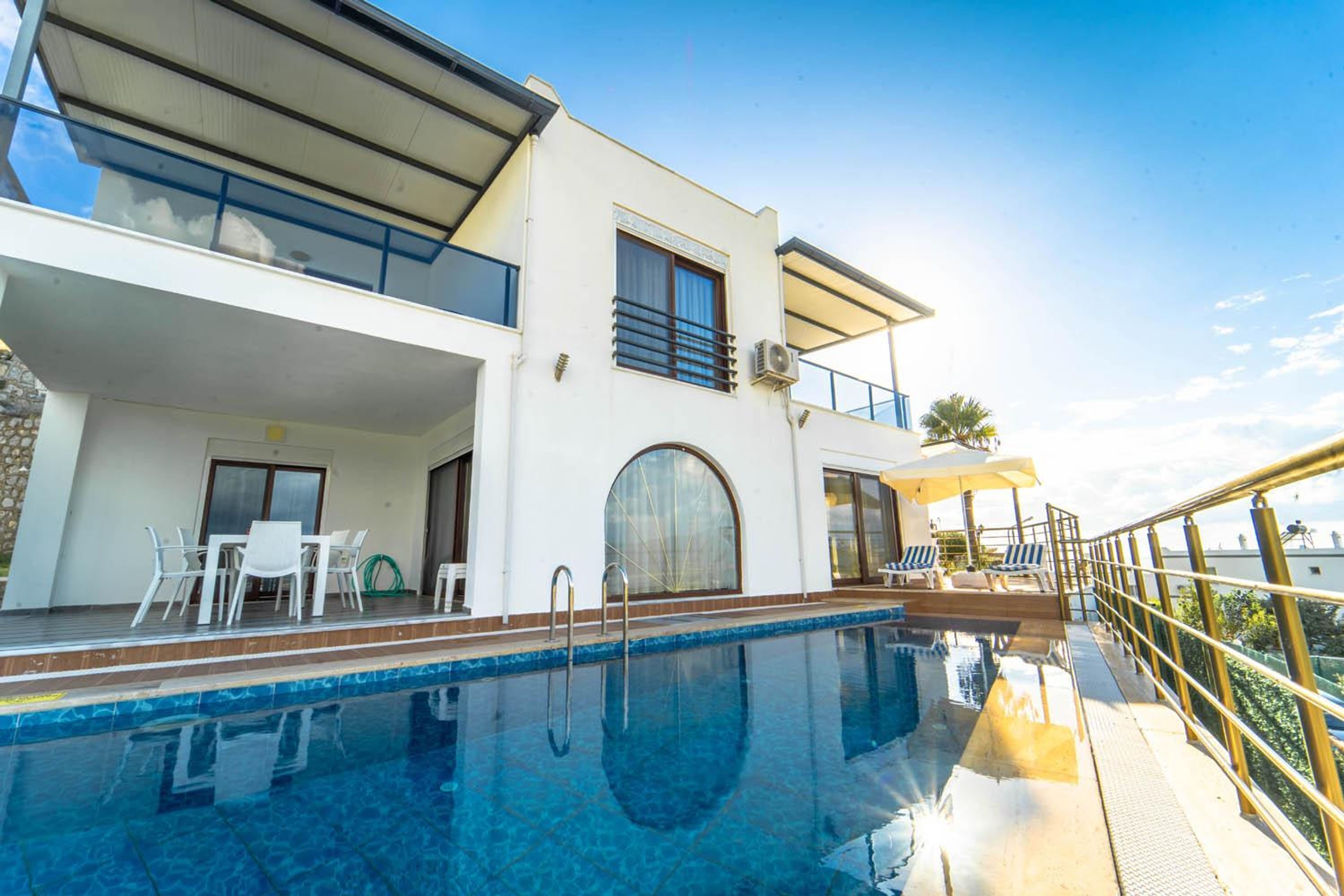 A modern building with a swimming pool, outdoor seating, and a balcony.