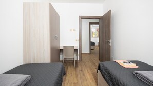 Een slaapkamer met twee bedden, een bureau en een stoel.
