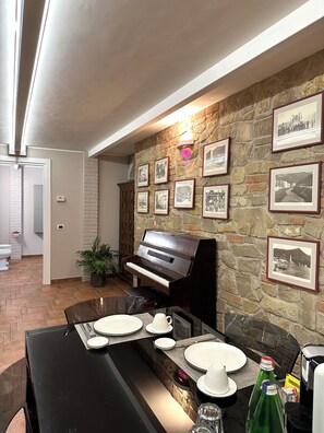 Ein Essbereich mit einem Klavier, einer Steinwand und gerahmten Bildern.
