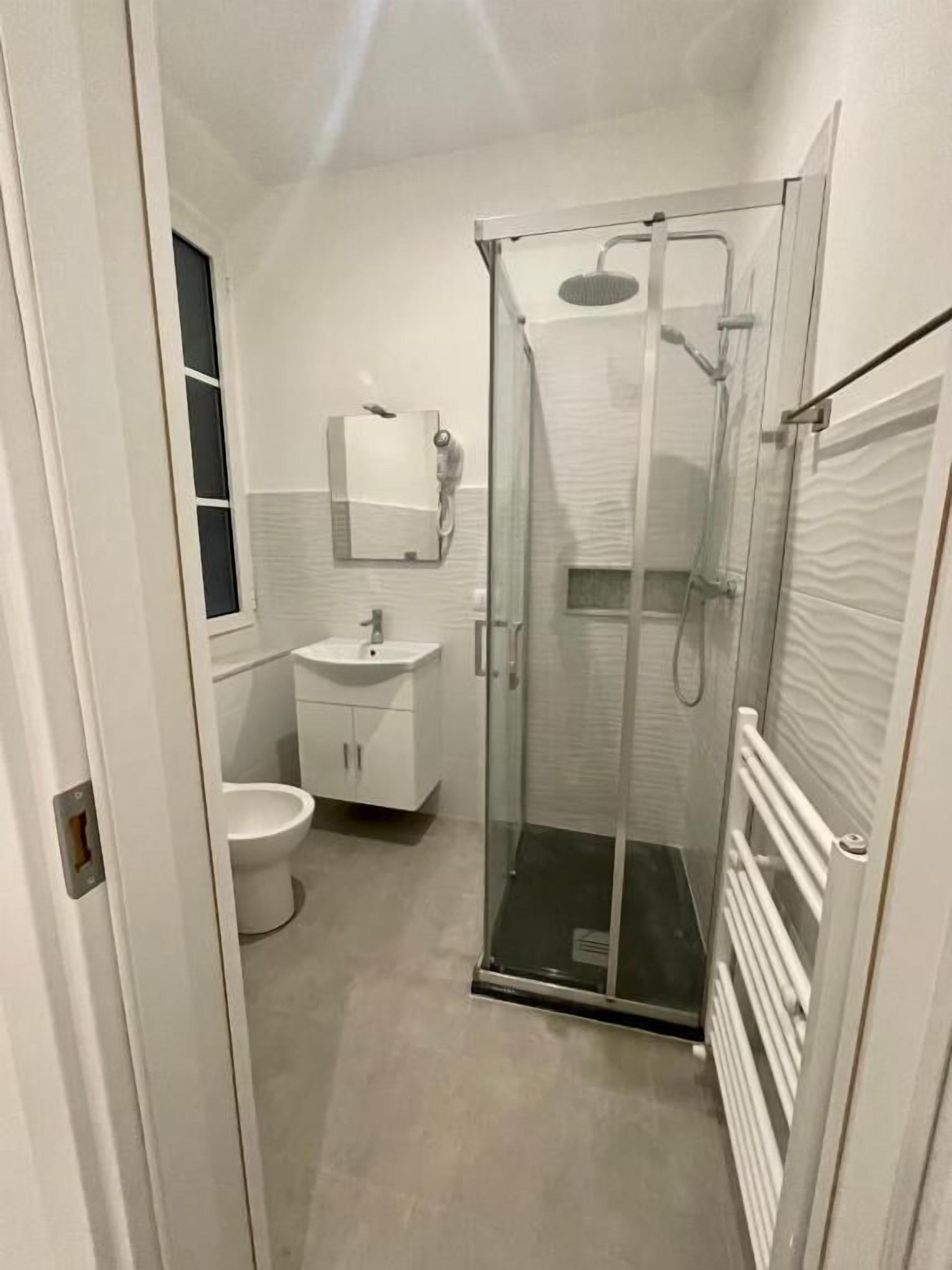 A modern bathroom with a glass shower enclosure, a toilet, and a sink.