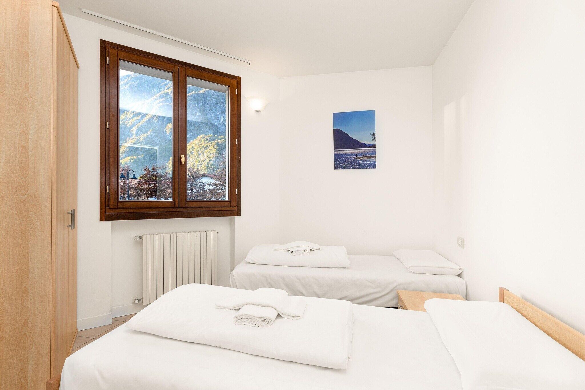A bedroom with two beds, a window with a mountain view, and a radiator.