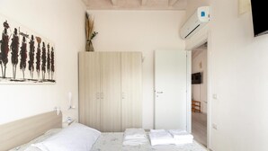 Un dormitorio con cama, armario y un cuadro en la pared.