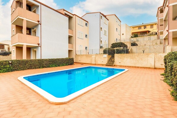 A residential building with a swimming pool, balconies, and a staircase leading to an upper floor. - Attic with terrace and swimming pool (Badesi)