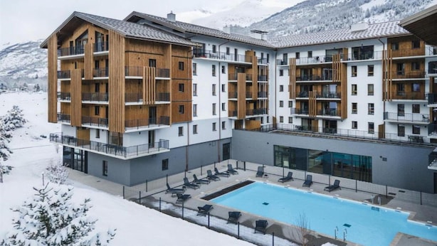 Un hotel moderno con varios pisos, balcones y una piscina.