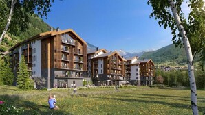 Un hotel moderno con varios pisos, amplias ventanas y vistas a las montañas.