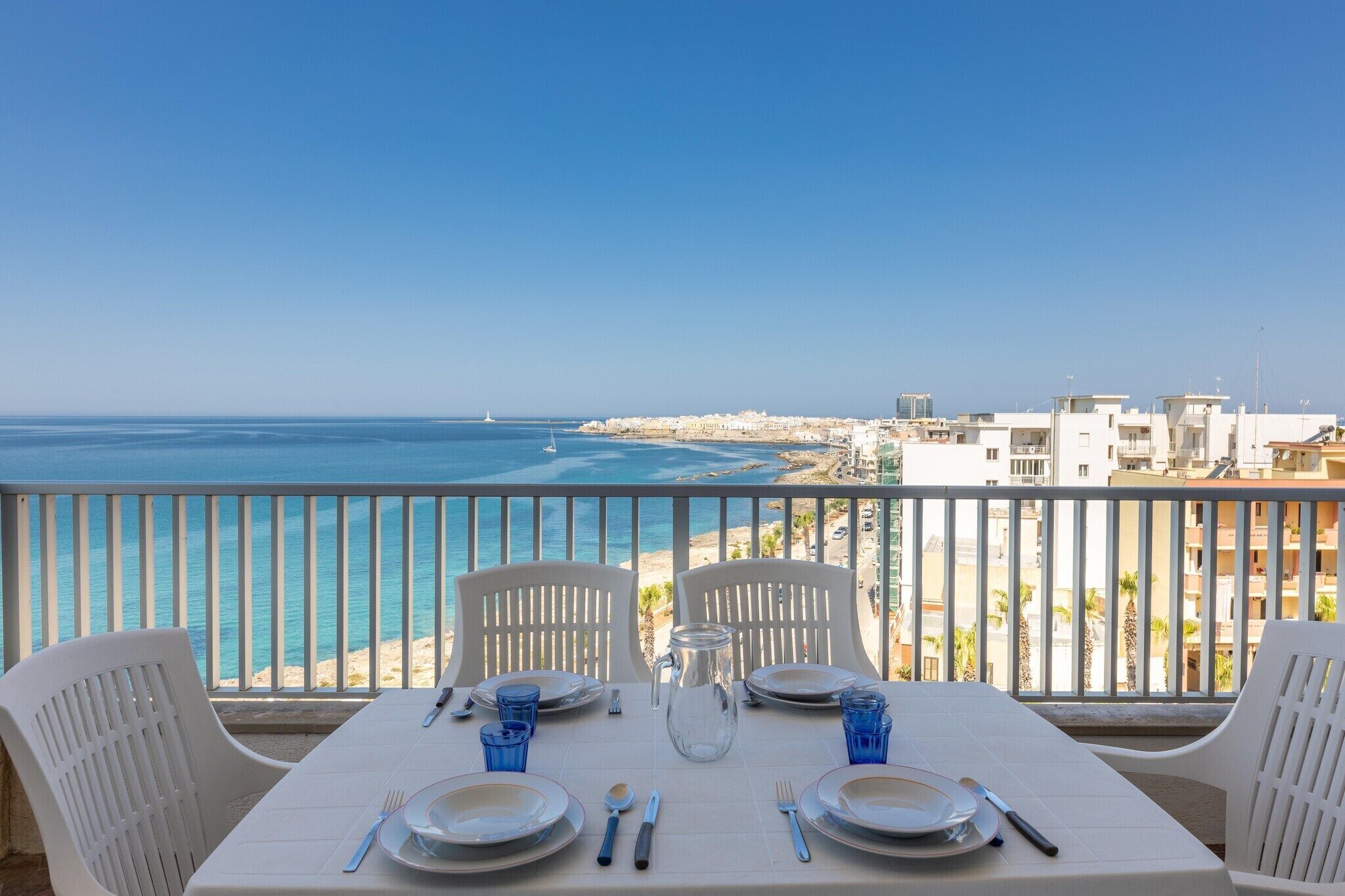 Ein Tisch für zwei Personen mit Blick auf das Meer und Gebäude im Hintergrund.