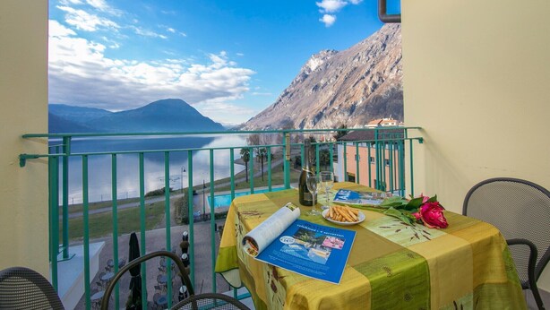 A balcony with a table set for two, overlooking a lake and mountains. - Appartement mit Seeblick auf den Luganersee (Porlezza)