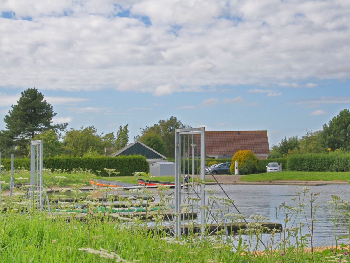 A calm water body with boats, a metal structure, and a building in the background.