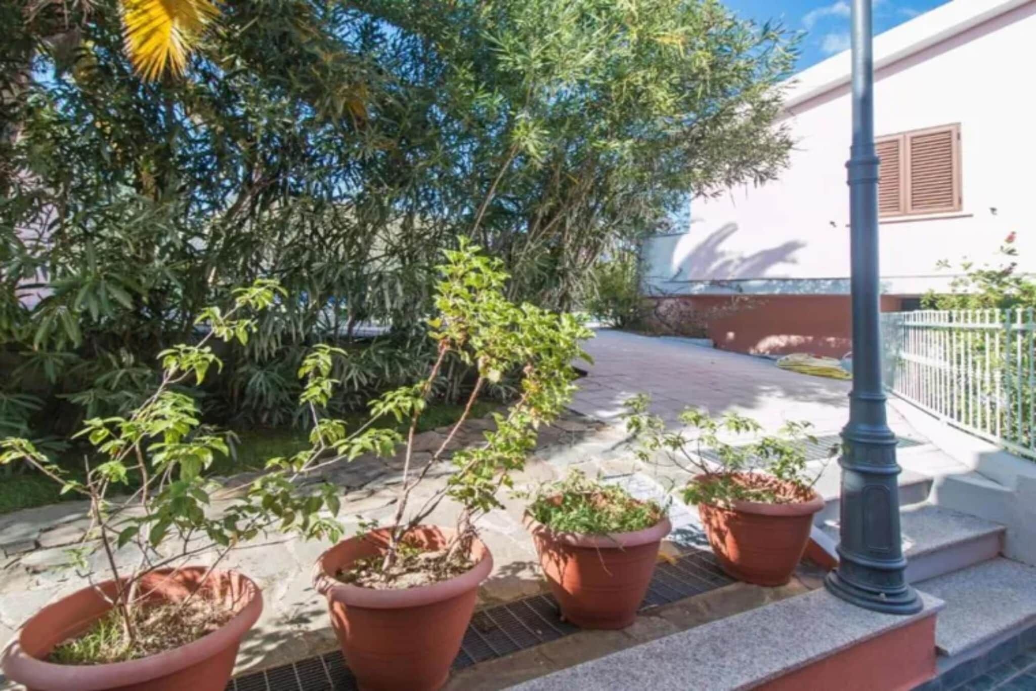 Ein Balkon mit Blumentöpfen, ein weißes Gebäude und ein Metallzaun.