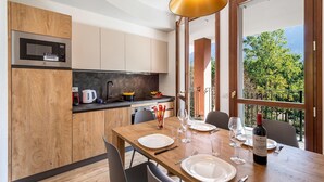 Cuina moderna amb microones, armaris de fusta i zona de menjador preparada per a dinar.