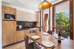 A modern kitchen with a microwave, wooden cabinets, and a dining area set for a meal. - Mobilehome in Porlezza am Luganersee (Porlezza)