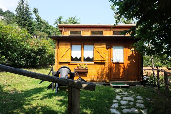 A wooden cabin with a front porch, a chair, and a potted plant. - village holiday house with a pool (Magliolo)
