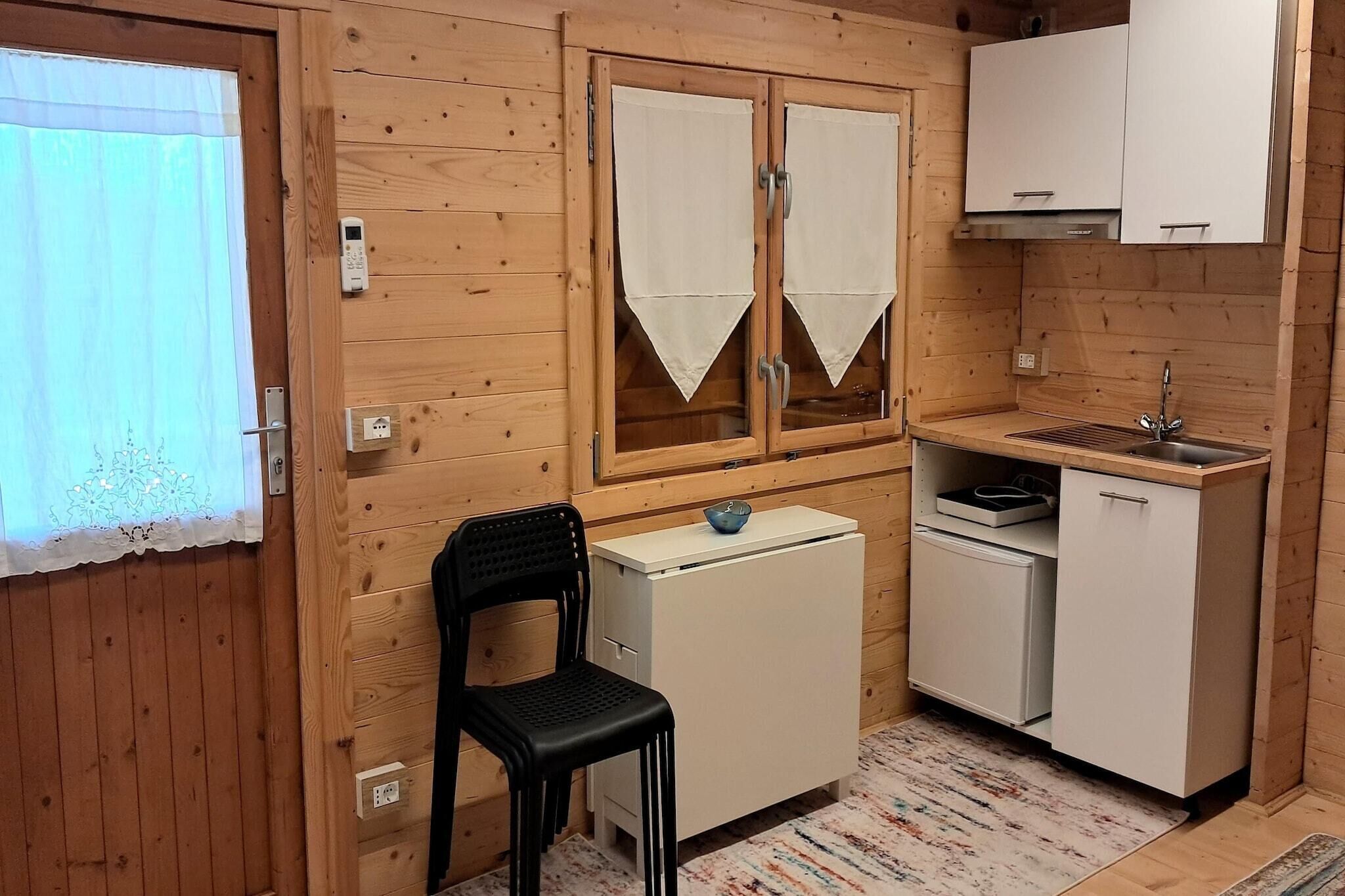 Une petite cuisine aux murs en bois, équipée d’un réfrigérateur, d’un évier et d’une chaise.