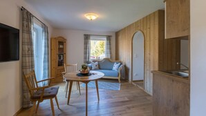 A cozy room with a wooden dining table, chairs, a sofa, and a kitchen area with wooden cabinets. - Apartment in Grainau am Badersee (Graifenau)