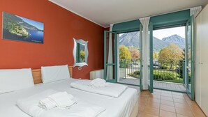 Ein Hotelzimmer mit zwei Betten, einem großen Fenster mit Bergblick und einem Gemälde an der Wand.