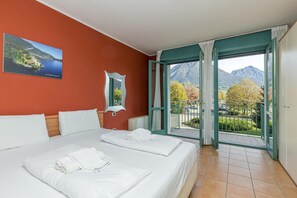 Une chambre d’hôtel avec deux lits, une grande fenêtre donnant sur les montagnes et un tableau accroché au mur.