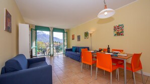 Ein Wohnzimmer mit einer Couch, einem Esstisch mit Stühlen und Blick auf Berge durch eine Glastür.