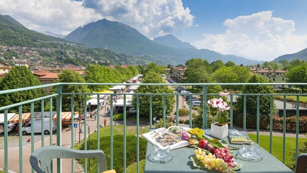 Ein Balkon mit Esstisch, mit Blick auf eine Stadt und Berge.