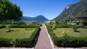 Ein gepflasterter Weg führt zu einem See, im Hintergrund Berge.