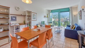 A modern kitchen with a dining area, a sofa, and a view of the city. - Appartement in Porlezza am Luganersee (Porlezza)